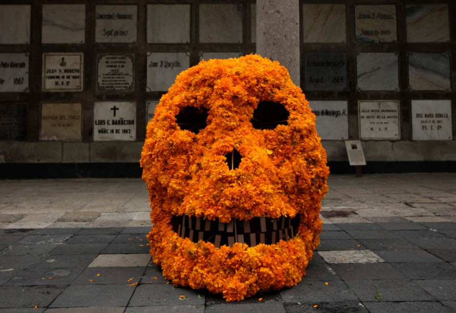 A skull covered in marigolds rests in front of a wall of graves, Mexico City, Oct. 27 2009 Halloween Day of the Dead Dia de los Muertos